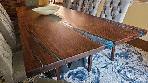 Closeup of dining room river table surrounded by chairs and a bowl sitting in the center.