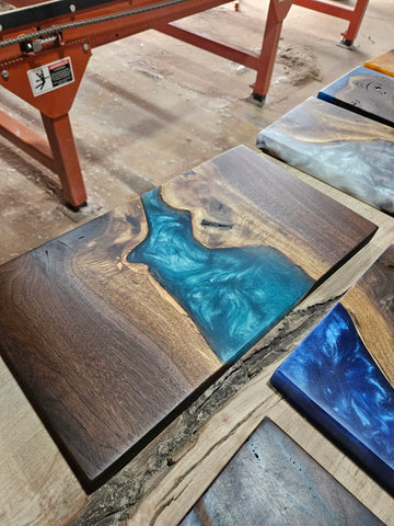 Dark wood charcuterie board with teal swirled epoxy resin in the middle.
