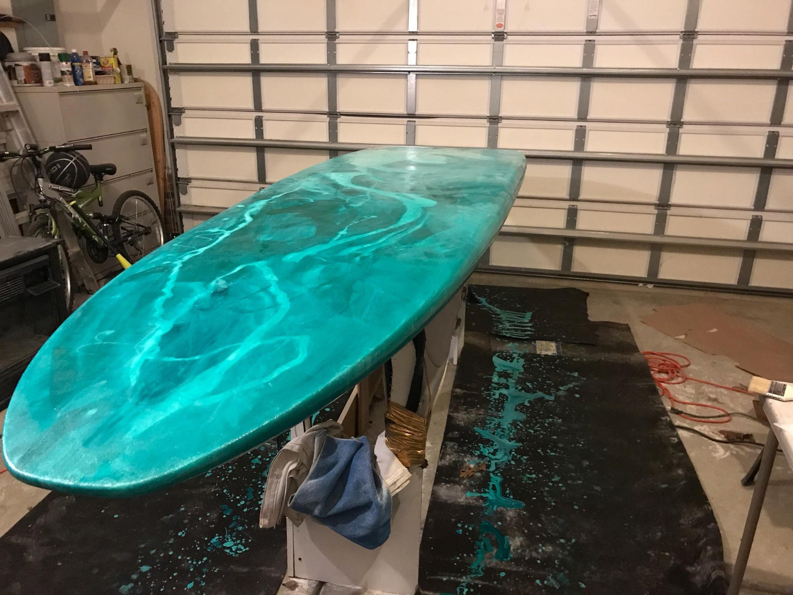 Turquoise colored paddleboard made with 4 ounce fiberglass cloth, epoxy resin and phthalo green and white pigments.