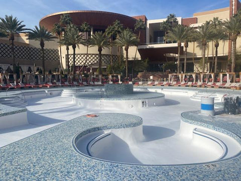 Large pool newly resurfaced with white gelcoat outside of hotel with palm trees.