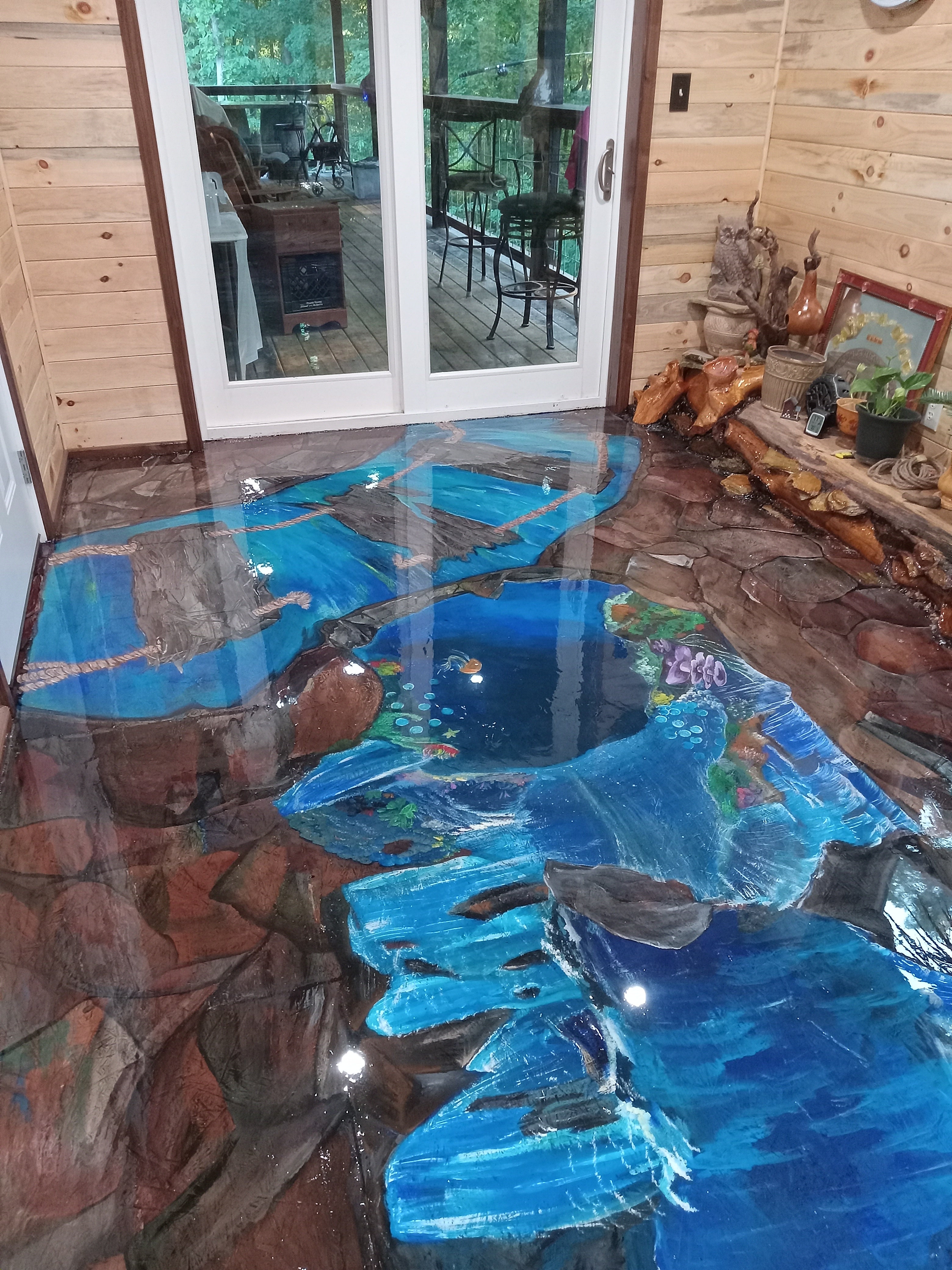 ProGlas 1000 table top epoxy resin decorated floor with bright blue river, large stones, painted plants and fish in front of french doors