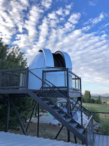 Large white fiberglass telescope dome observatory at the top of stairs.