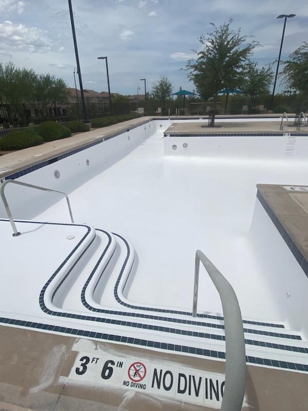 Large olympic size pool resurfaced with white polyester gel coat and blue tiles.
