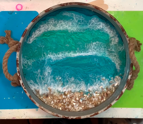 Round serving tray with beach scene made with blue, teal and white pigments along with epoxy resin and sand.