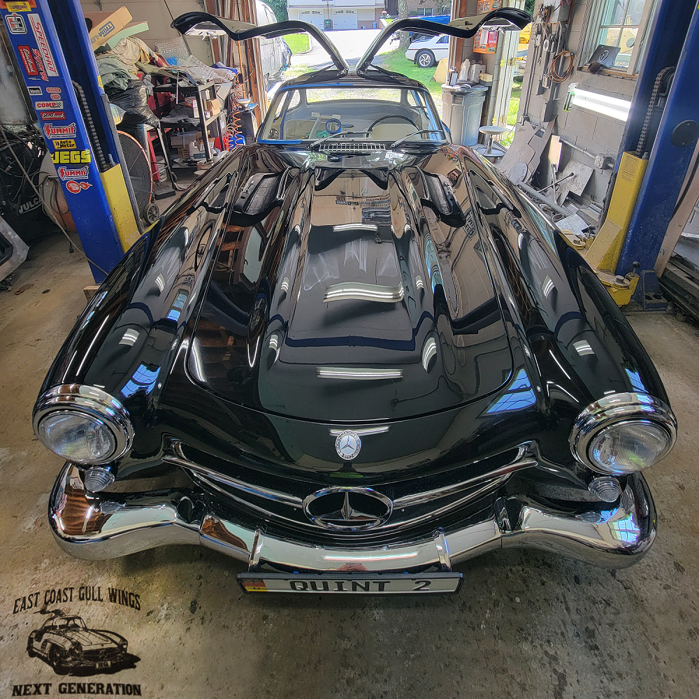 Finished black gullwing with doors that open to the top sitting in workshop.