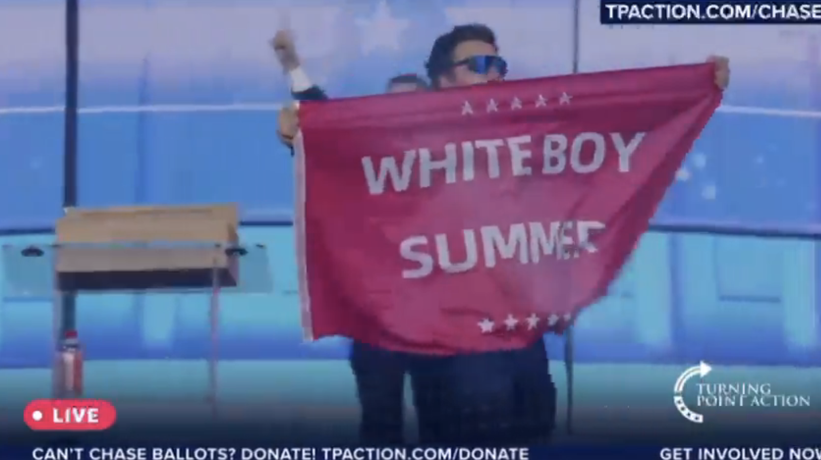 Jack Posobiec holds a banner reading "Whiteboy Summer" at a Turning Point Action event